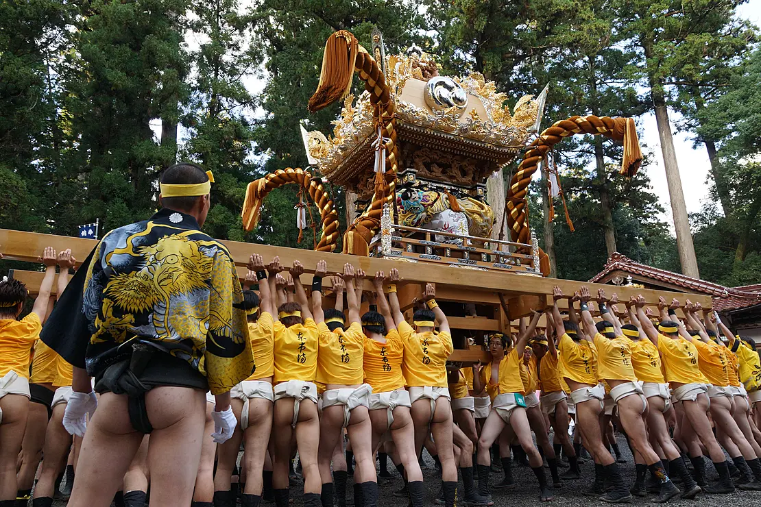 数の人々によって担がれている、豪華な装飾が施された金色の神輿