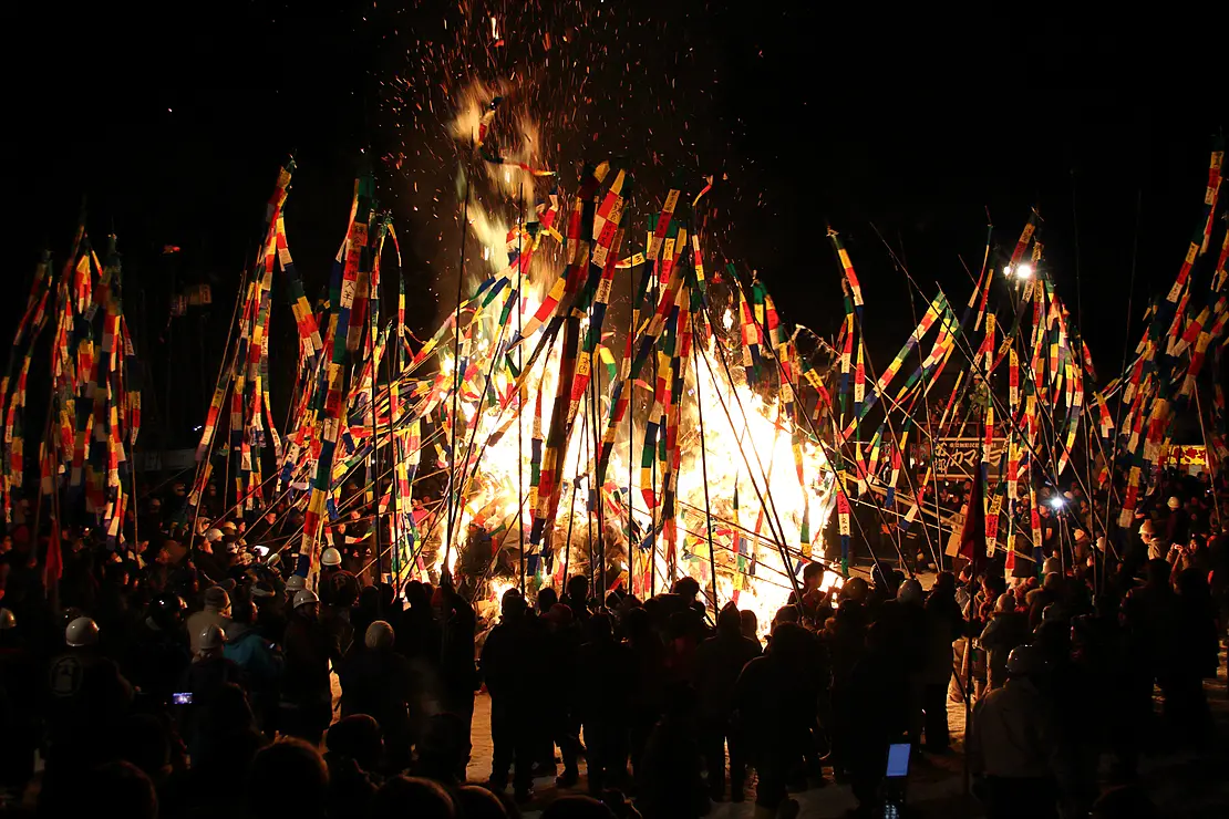 炎の周りに竹を持った人が集まっている