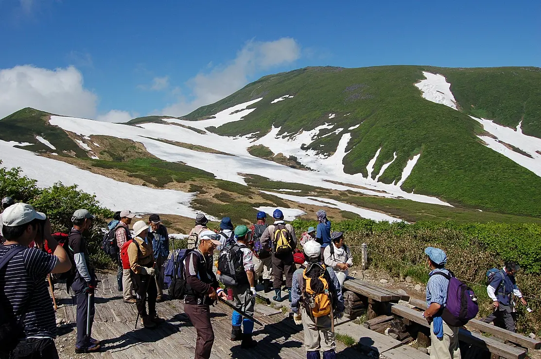 雪渓が残る月山と登山客