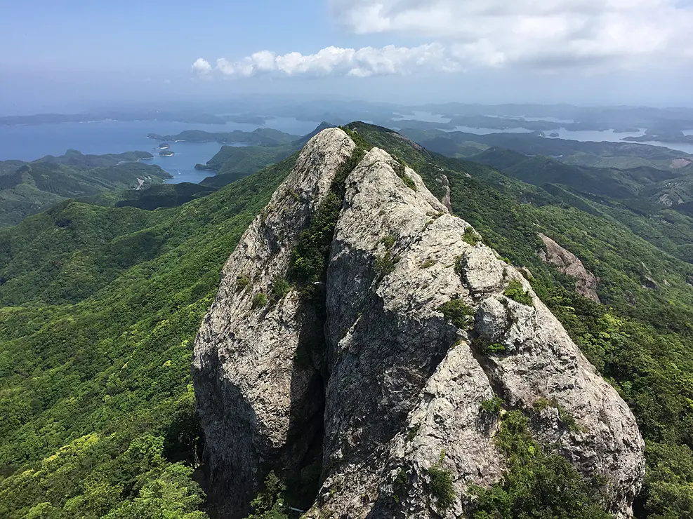 九州百名山の白嶽は、古代から信仰対象として崇められてきた対馬のシンボルです。山頂までは約2時間、標高518ｍながら、石英斑岩がむき出しの山頂付近の高度感は圧倒的。外洋と浅茅湾、大陸系植物が自生する濃緑の原始林が眼下に広がる大パノラマを楽しめます。
