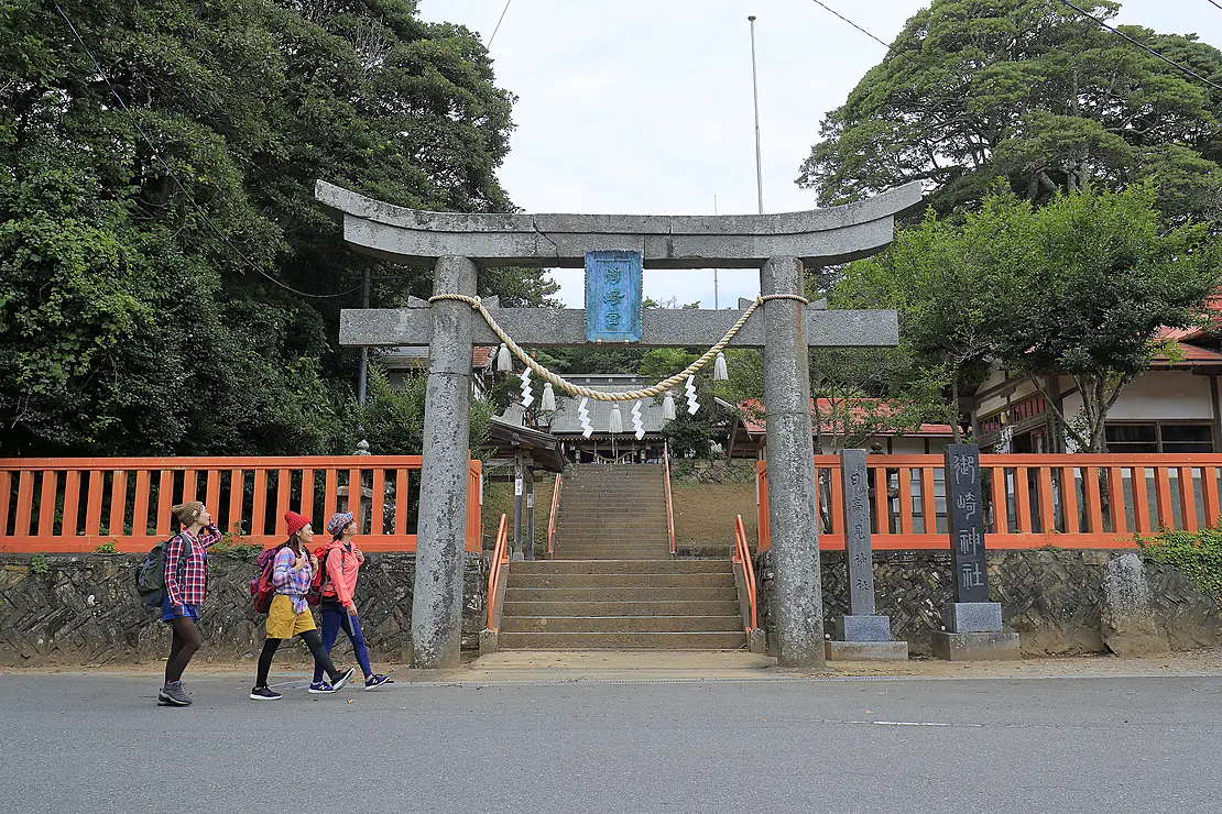 鳥居の前をハイキングする人たち