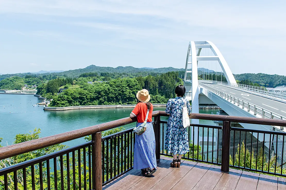 橋のたもとから島を眺める女性たち