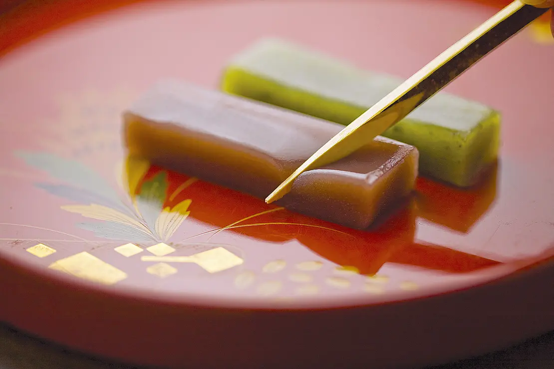 小豆と抹茶のおいしそうなういろうが赤い皿の上に2本並んでいる