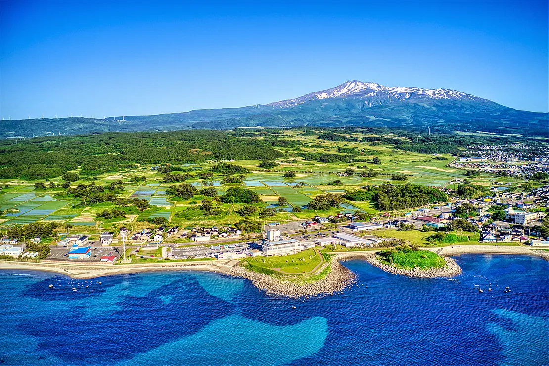 山の麓に田園地帯と海が広がっている