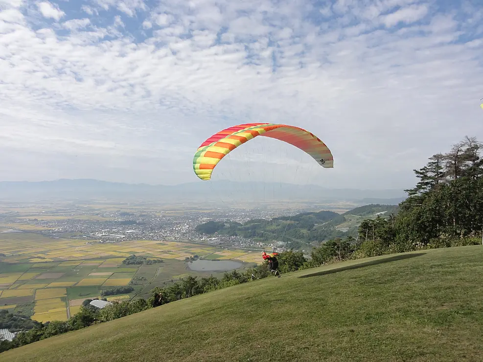 山の斜面から飛び立つパラグライダー