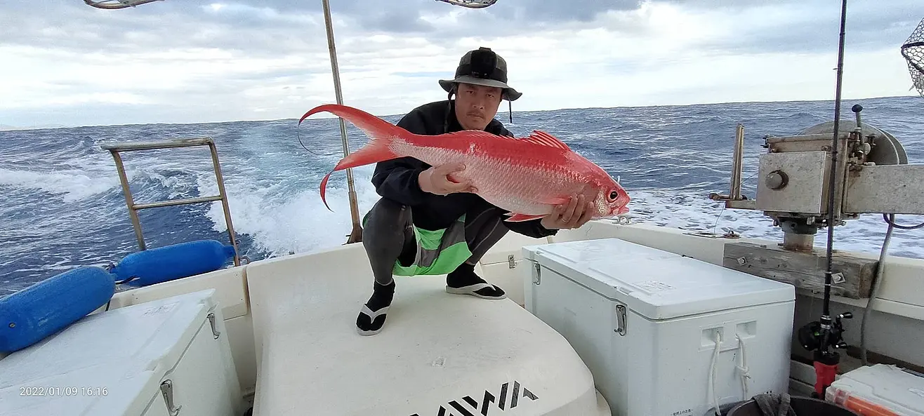 船の上で釣った大きな魚を持つ人