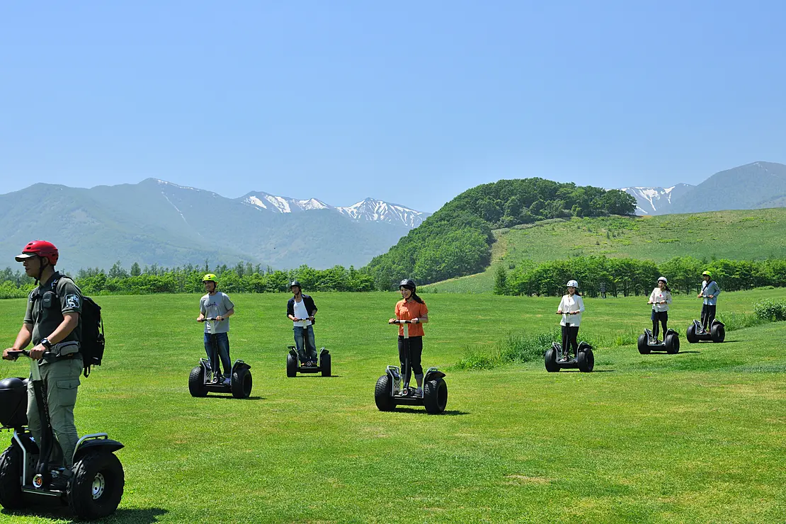 セグウェイに乗って芝生を走る人々