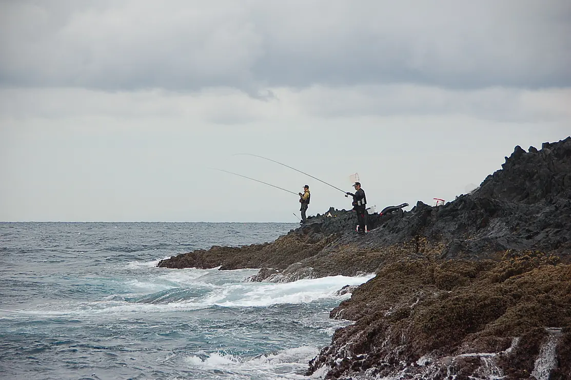 岩の上で2人の男性が磯釣りしている