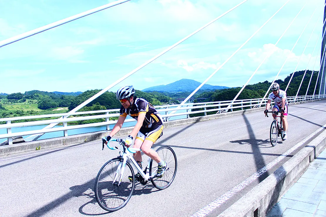 湖に架かる橋をサイクリングする男性