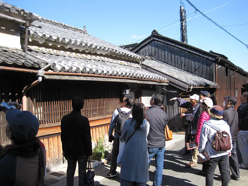 伝統的建築物の前でガイドの解説を聞く人々