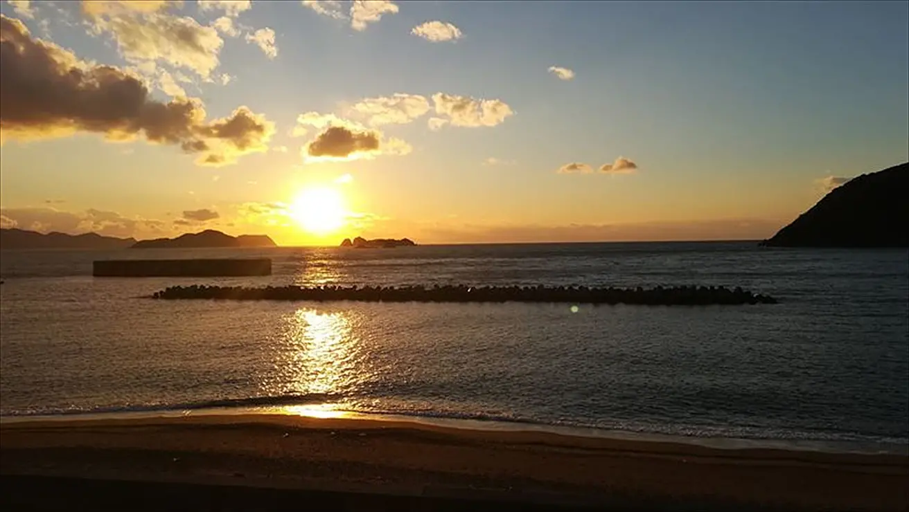 水平線の向こうに落ちていく夕日が海を橙色に染める