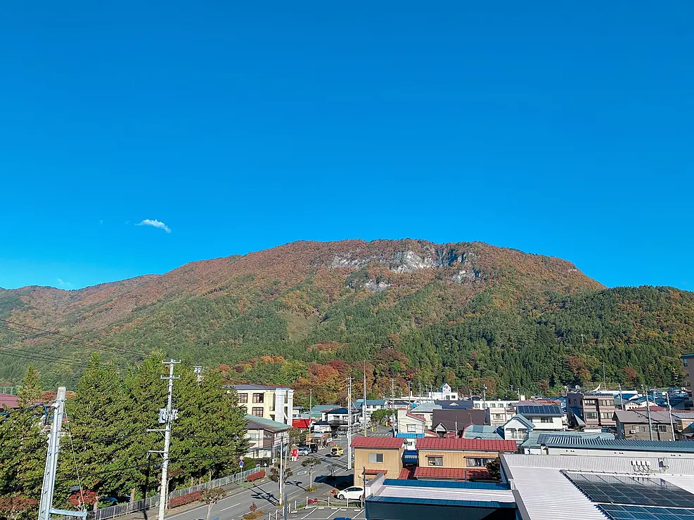 街並みの奥にそびえる紅葉した山