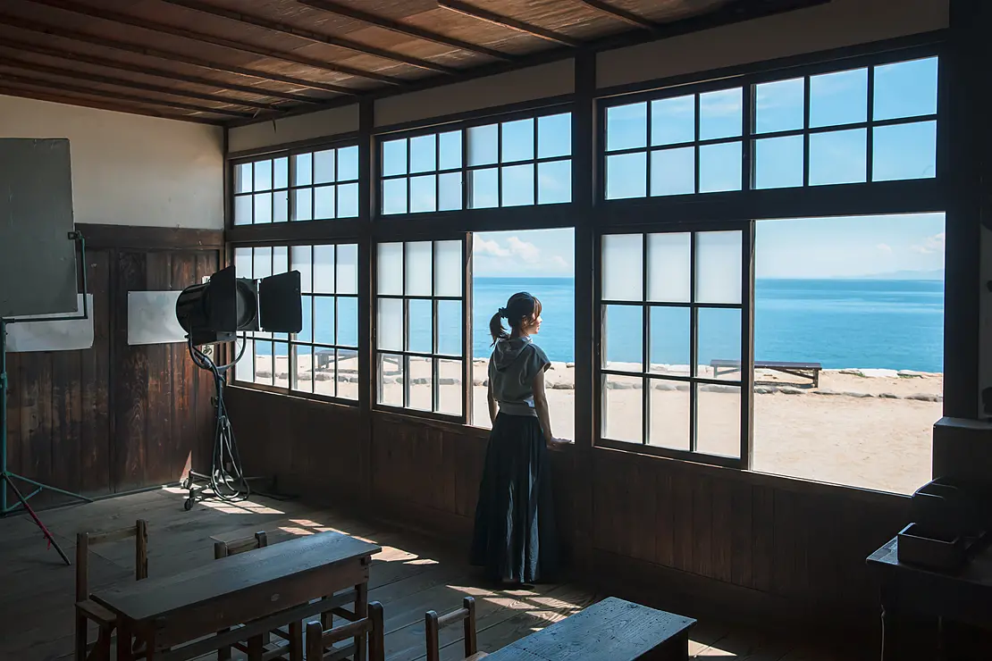 若い女性が校舎の教室の窓から瀬戸内海を眺めている