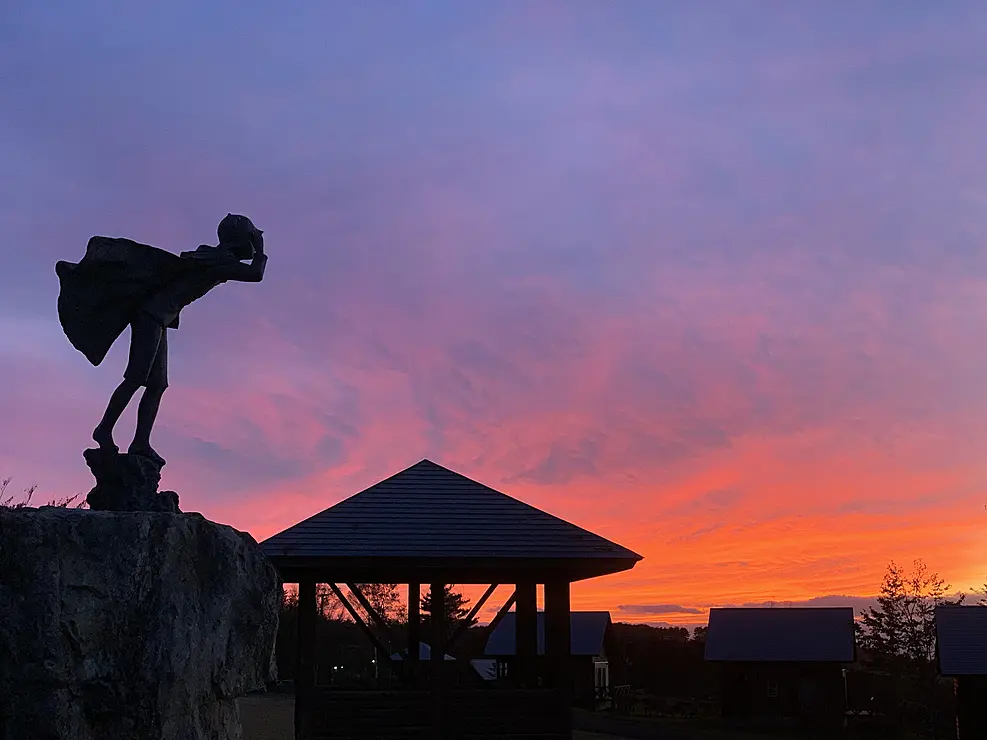 夕焼けのなかの少年の姿の彫刻