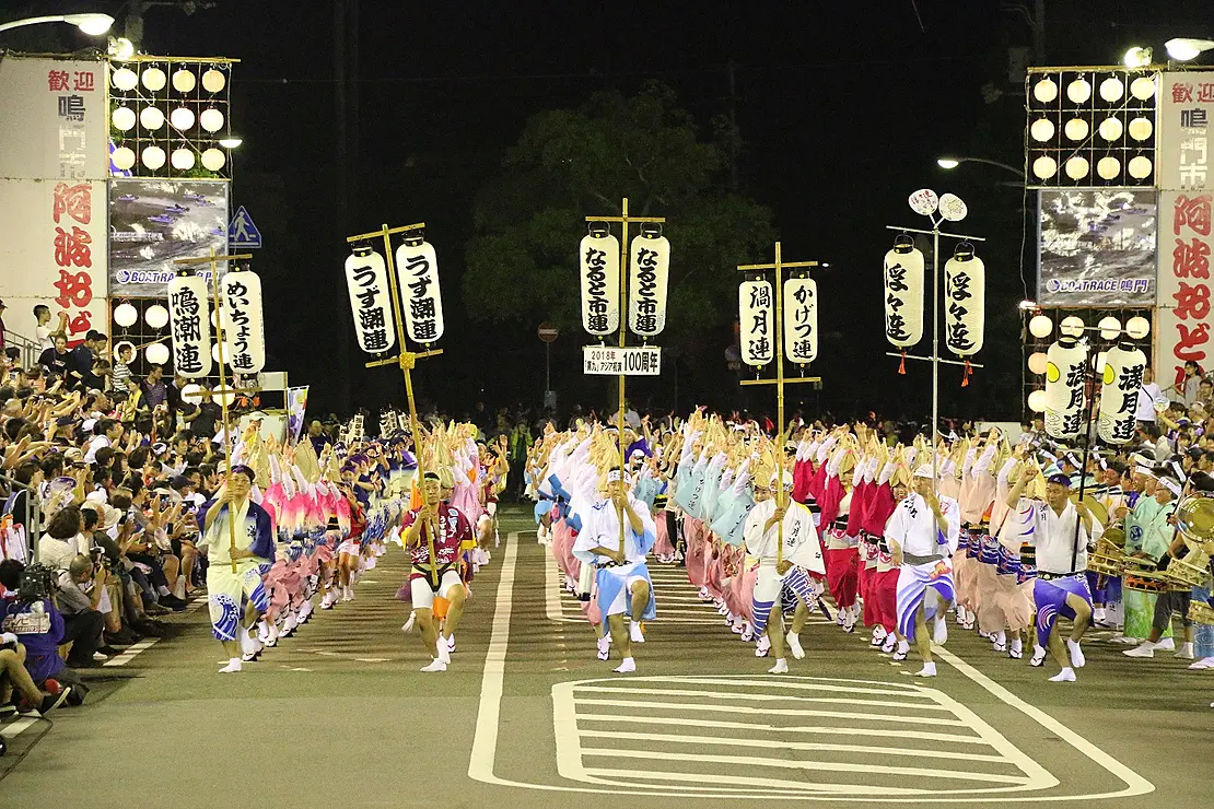 夜に提灯をともし、列になって阿波踊りを踊っている