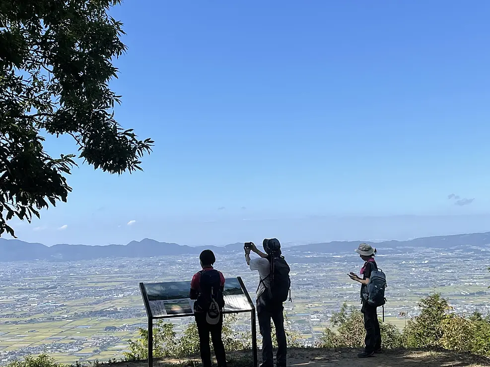 龍王山山頂の看板の前で写真を撮る人々　眼下に広大な奈良盆地が広がる