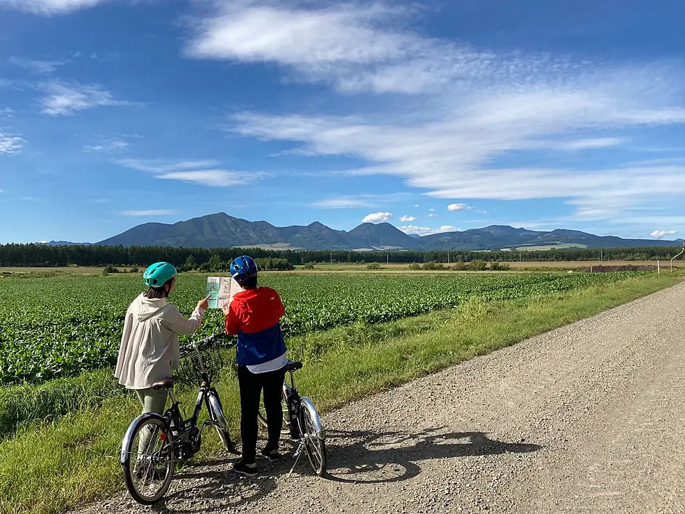 畑の道で地図を確認するサイクリスト