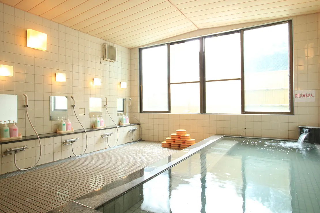 広々とした清潔感のある温泉の内風呂。大きな窓の外には豊かな自然が広がっている。