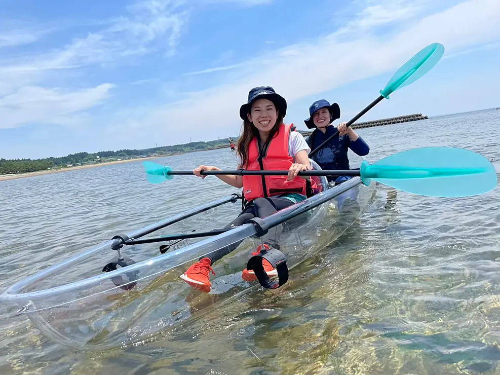 透明なカヤックを漕ぐ二人の女性