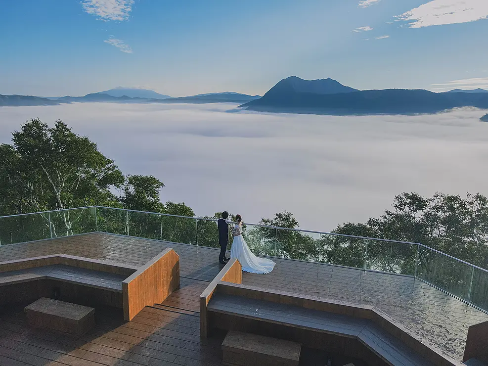 雲海の広がる展望テラスでウェディングフォトを撮る人