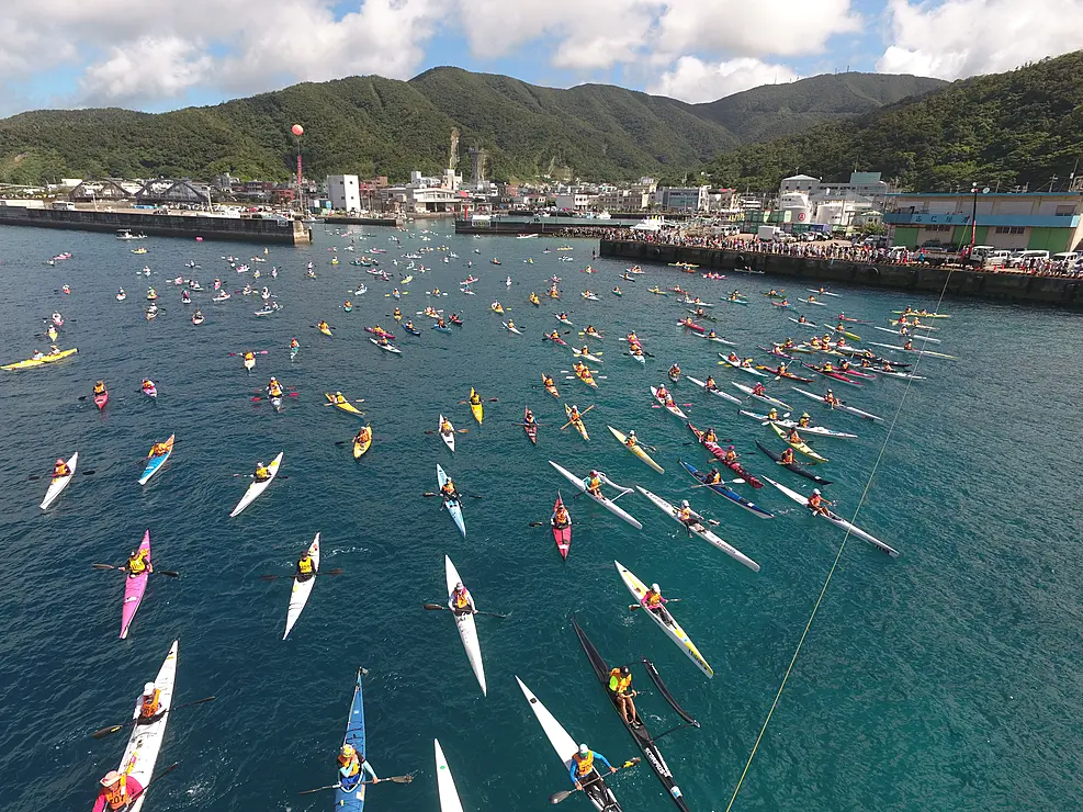 大島海峡の海面に数百艇もの色とりどりのシーカヤックが浮かび、選手たちが一斉にスタートする瞬間の空撮写真