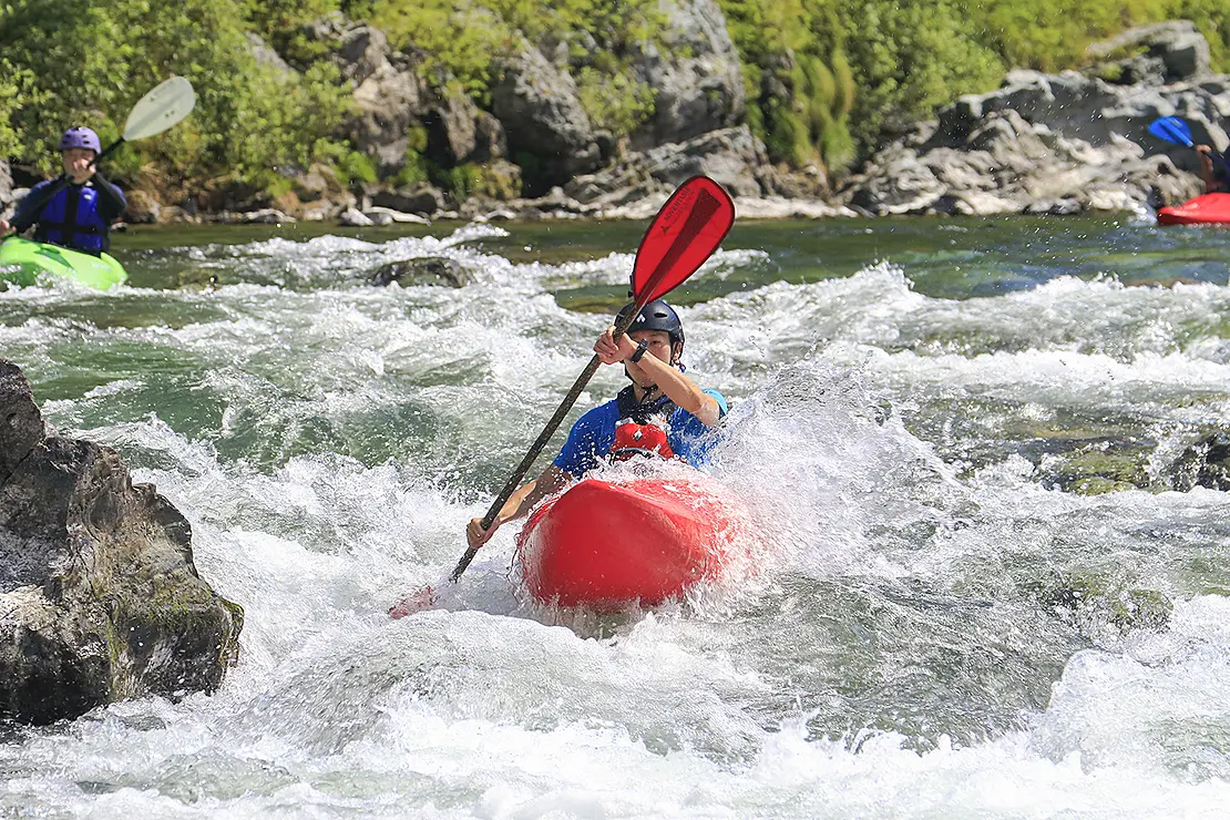 白く波立つ急流をカヤックで漕ぐ人