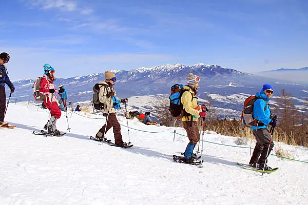 八ヶ岳をバックにスノーシューを楽しむ人々