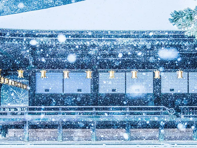 雪の降る中、伝統的な寺院の建物が写っている