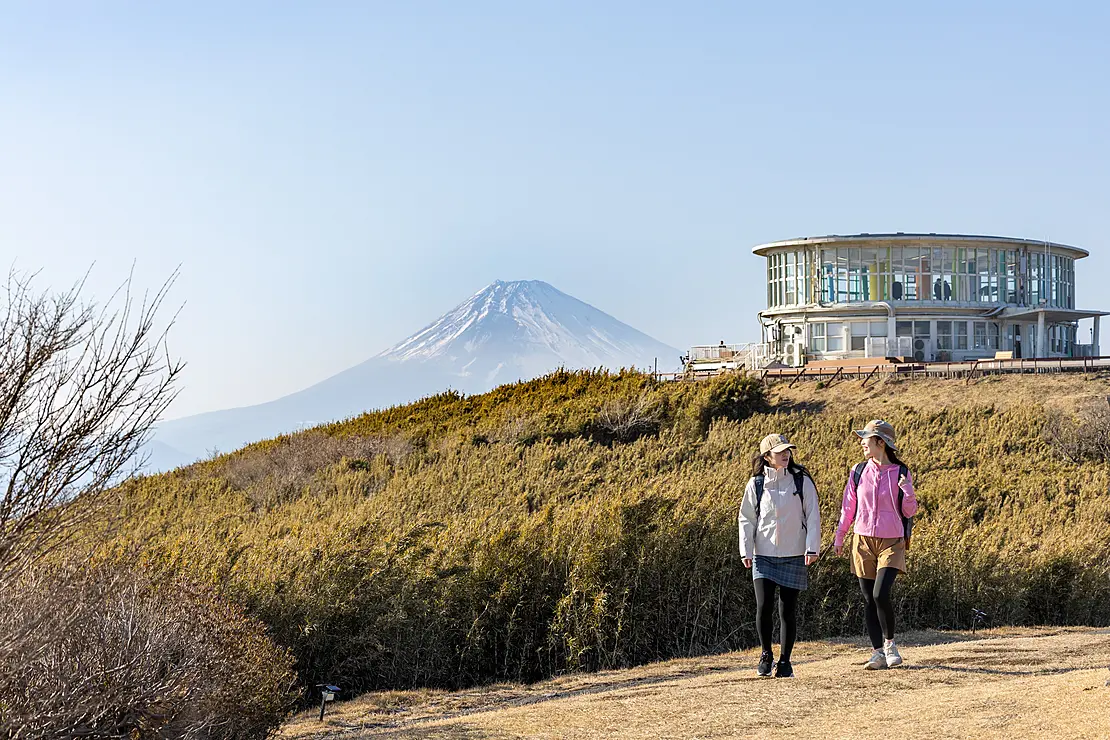 富士山をバックに登山道を歩く2人