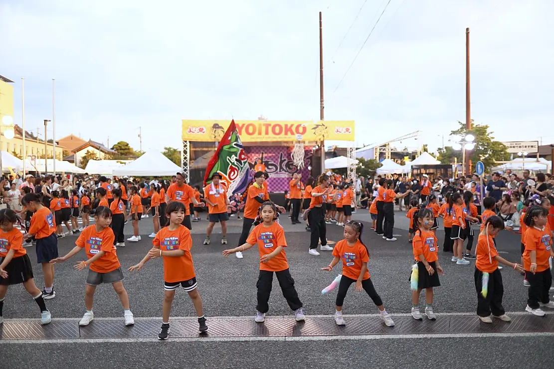 オレンジ色の衣装を着て踊る参加者