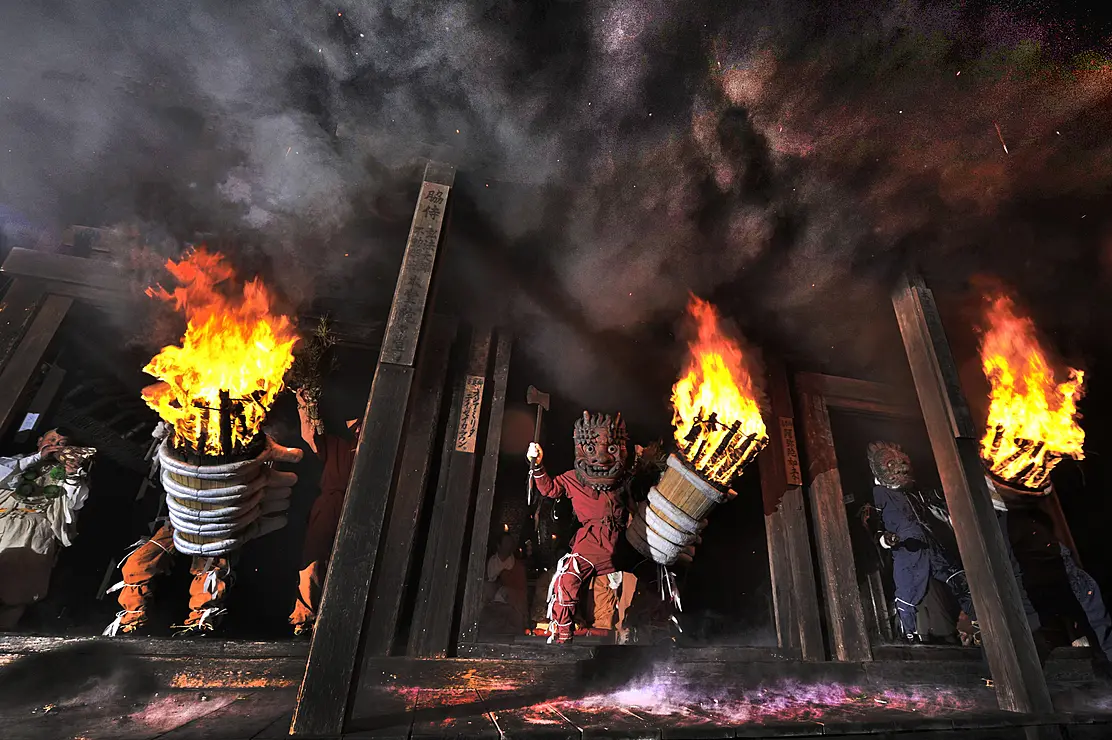 鬼の面をかぶり、左手に大きな松明を掲げた人