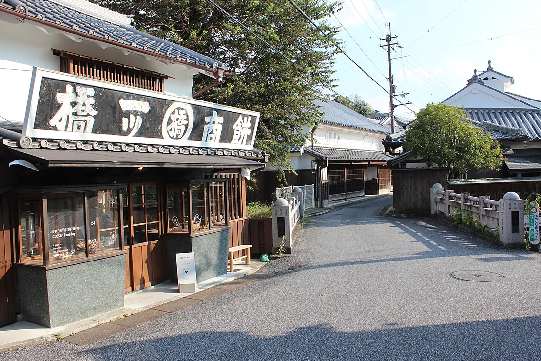 伝統的な家屋が道沿いに並んでいる。手前の建物には「餅商一ツ橋」の看板が掲げられている