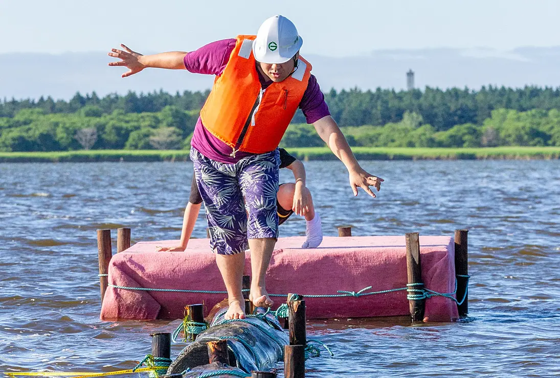 湖上で丸太渡りをする人