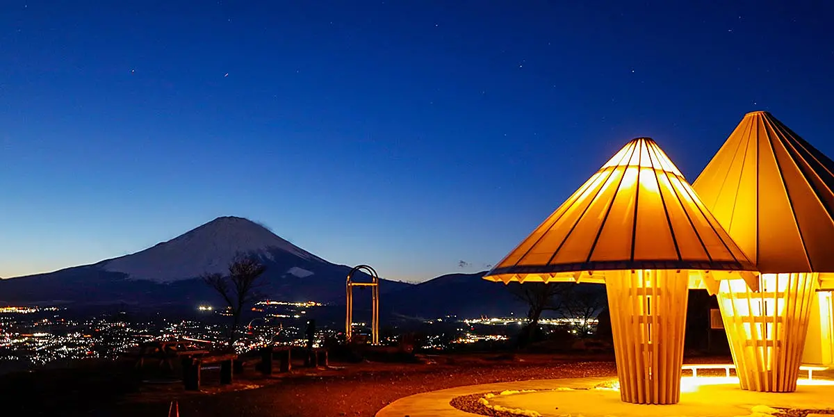 オレンジ色に光るきのこ形の建造物と夕暮れの富士山