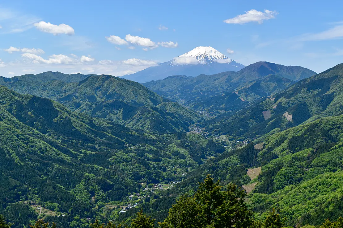 富士山を遠くに臨み山の谷間に村がある