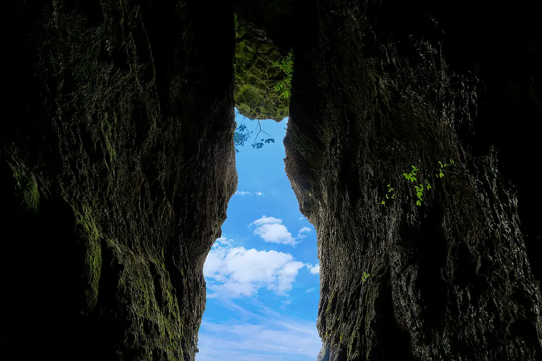 熊本県南阿蘇村のパワースポット『免の石』。地震で落ちた大きな石の代わりに現れた、招き猫の形に見える洞窟の開口部から見上げる青空