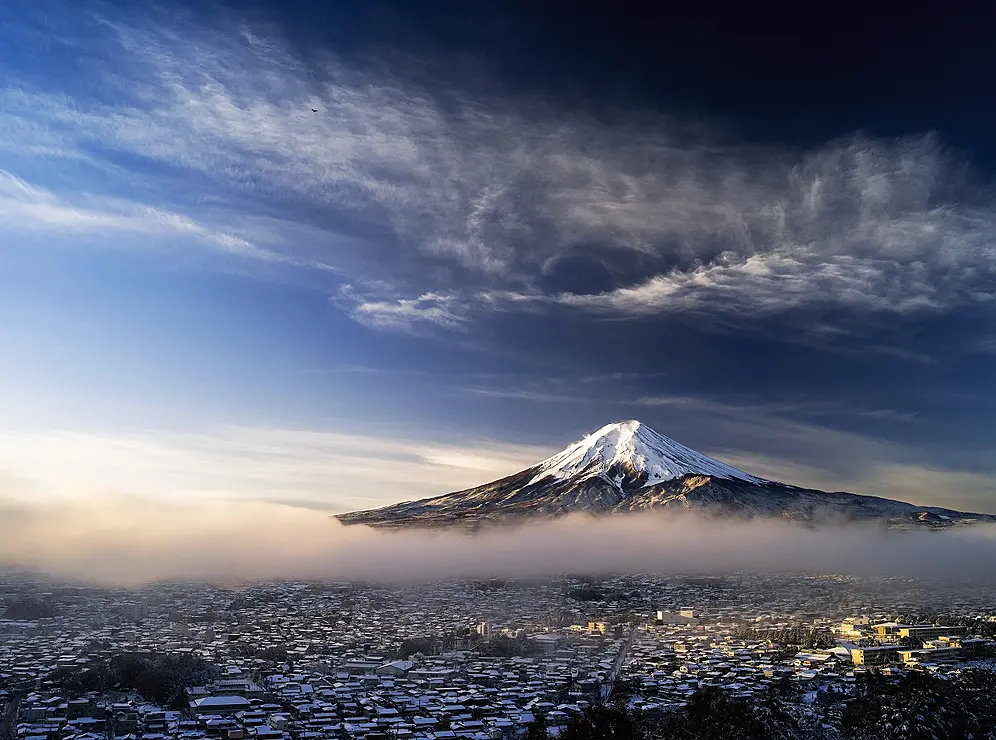 雪景色の街の奥にそびえる富士山
