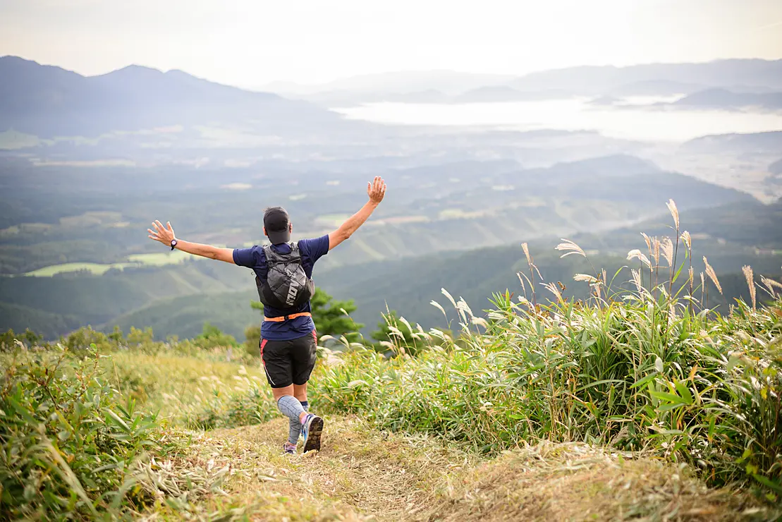 両手をあげながらトレイルランニングをする男性