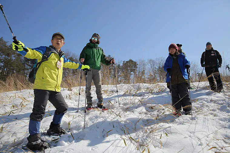 ガイドがスノーシューツアー参加者に説明中
