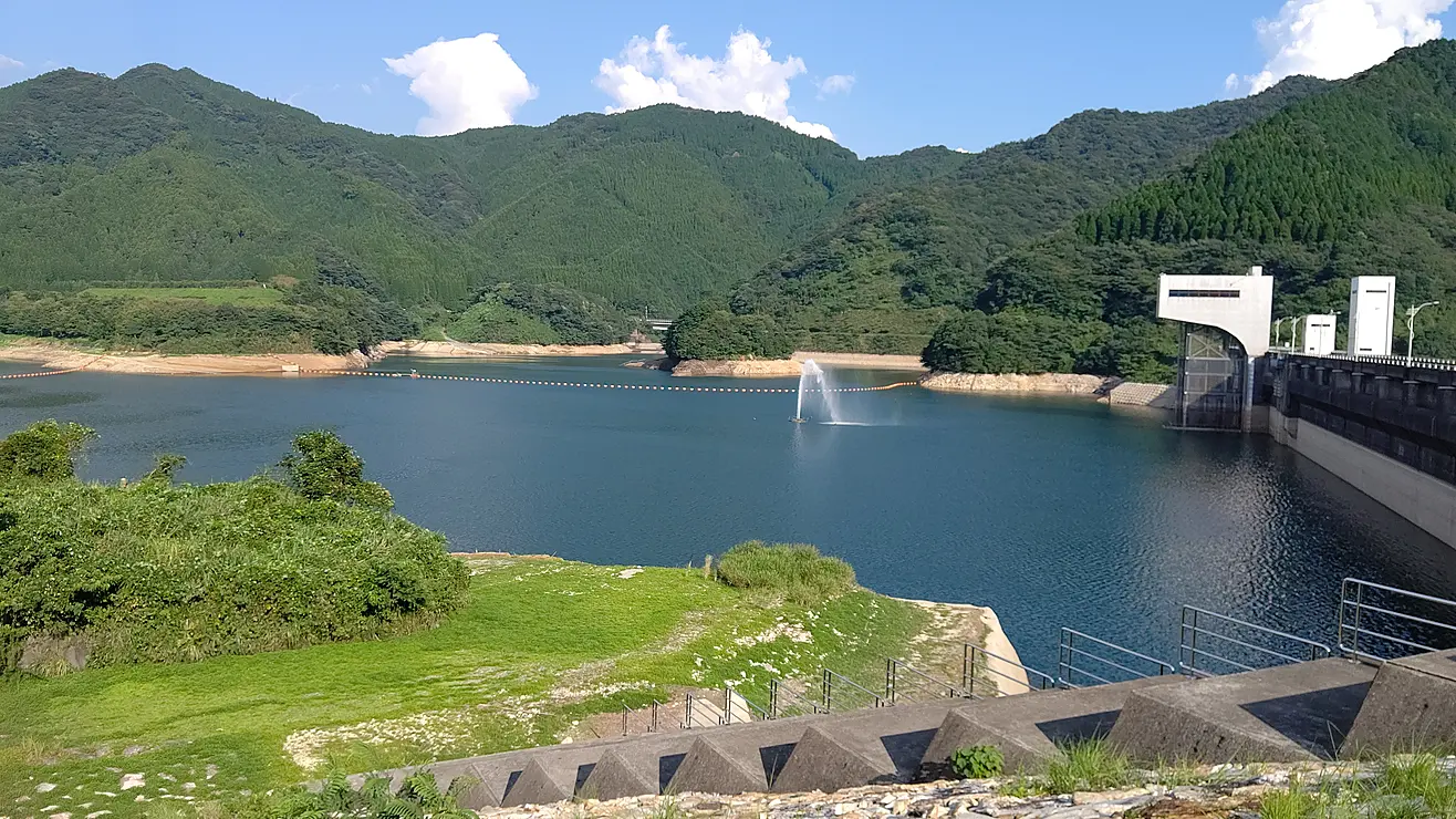 周囲の山々と青空が湖面に映る竜門ダムの全景