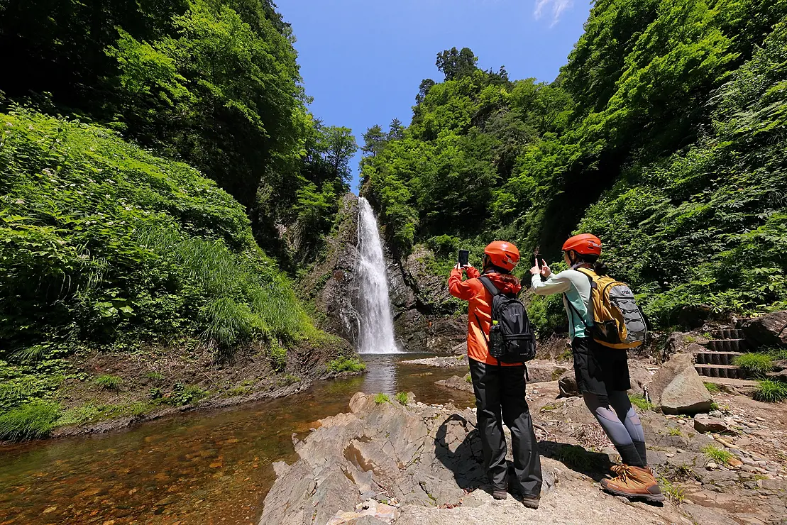滝を見るヘルメットを被った二人の女性