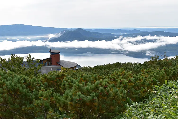 緑に囲まれた家と霧に包まれた湖と山