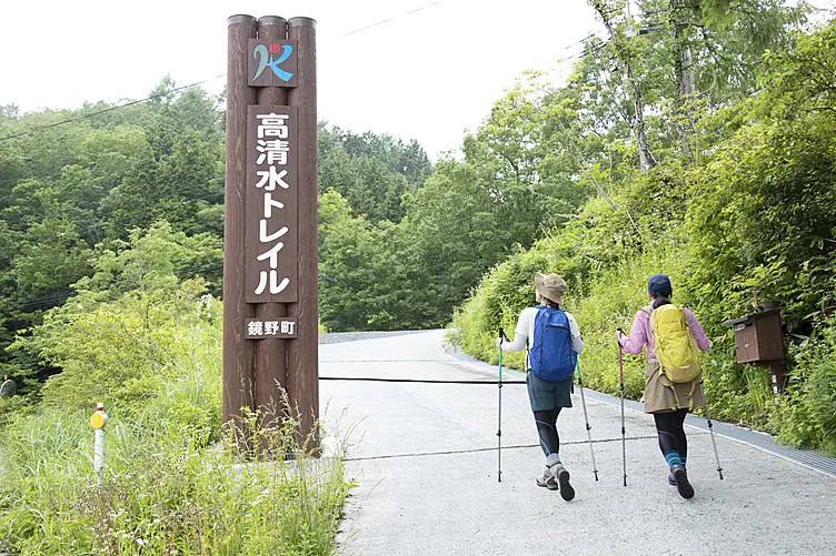 高清水トレイルの看板と青いザックの女性と黄色いザックの女性