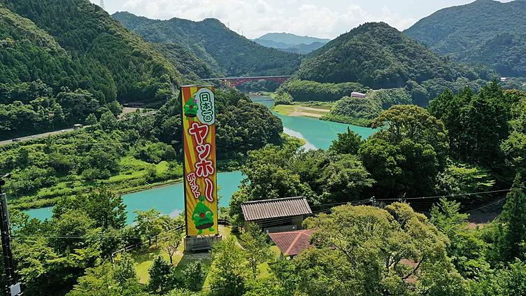 椿山ダムの青い湖面と山並み　手前の東屋の横に「日本一のヤッホーポイント」の看板