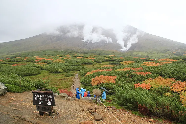 旭岳と登山道に立つ人々