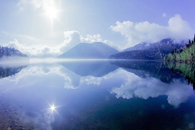 雲と山を映す静かな湖面