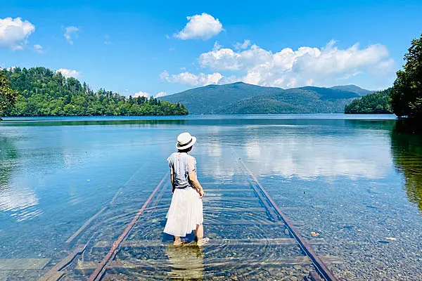 湖に沈む線路と白い服を着た女の人