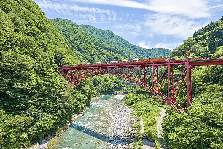 美しい渓谷に架かる橋をトロッコ電車が通る