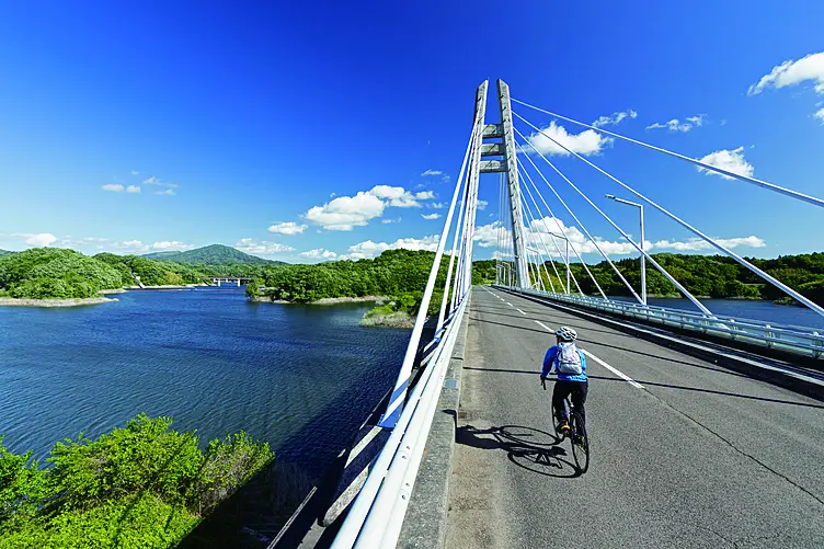 湖の上に架かる白い橋をサイクリング