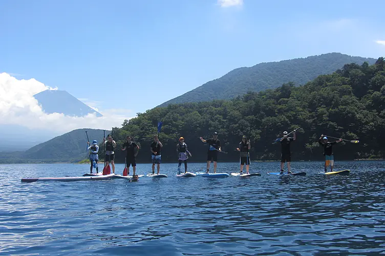富士山を背景に湖でSUPを楽しむ人たち